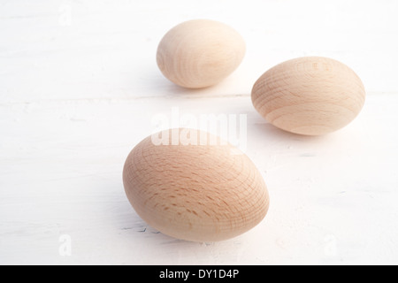 Three wood eggs arranged from front to back on one side of the photo. The wood eggs are in natural light and colour. Stock Photo