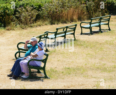 Couple sitting on park bench, UK Stock Photo