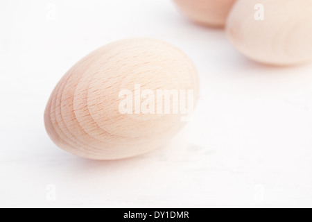 Three wood eggs arranged from front to back on one side of the photo. The wood eggs are in natural light and colour. Stock Photo