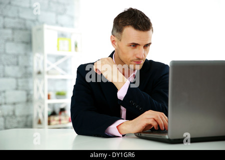 Confident businessman working on a laptop at office Stock Photo