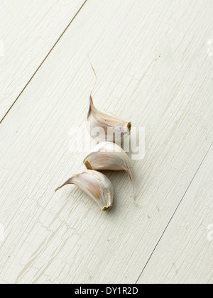 Three Garlic Cloves on light wood background Stock Photo
