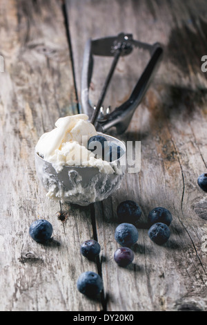 Ice cream in metal spoon with blueberries on old wooden table Stock Photo