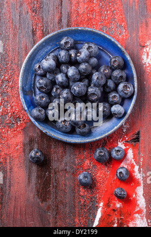 Top view on blue ceramic plate of blueberries over red wooden table Stock Photo