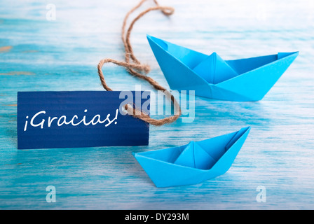 Label with the Spanish Word Gracias which means Thanks and Two Boats in the Background Stock Photo