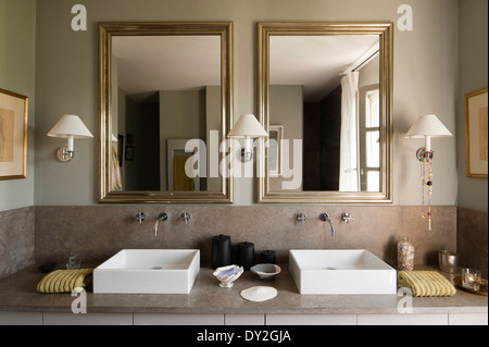 Modern twin square basins and mirrors in bathroom in grey tones. The wall paint is by Emery & Cie Stock Photo
