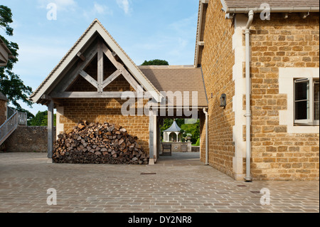 Exterior facade of log store as part of 19th century farmhouse with paved drive Stock Photo