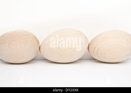 Three wood eggs arranged from front to back on one side of the photo. The wood eggs are in natural light and colour. Stock Photo