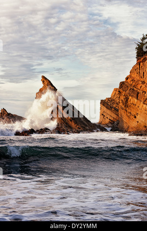 Evening waves explode against the sandstone cliffs at Oregon’s Shore Acres State Park from Simpson Beach. Stock Photo
