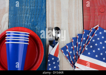 High angle photo of a Fourth of July picnic table setting. The red white and blue items are on a wood table Stock Photo