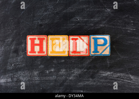 Colorful childrens blocks spelling out Help on a chalk board. Horizontal format. Stock Photo