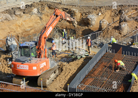 Track laying digger machine adapted for working on concrete pile heads steel fixer assembling steel reinforcement cage building construction site UK Stock Photo