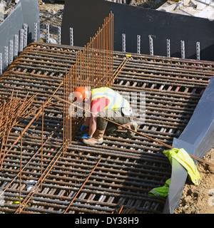 Construction site steelfixer tying steel reinforcement cage together as part of foundations for new building London England UK Stock Photo