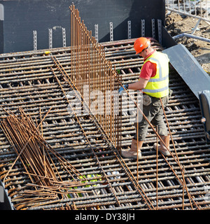 Steelfixer tying steel reinforcement cage together as part of foundations for new building Stock Photo