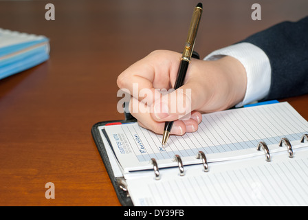 businessman hand holding a pencil while making notes in workbook Stock Photo