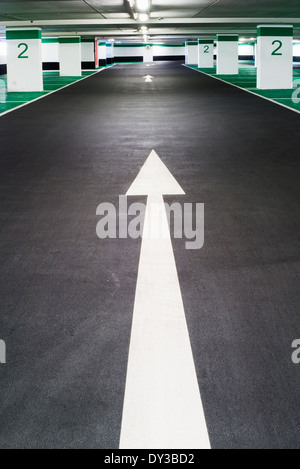 White arrow painted on tarmac in an empty car park. Stock Photo
