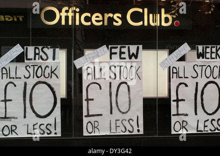 Sale signs in an Officers Club shop front with people walking past. Stock Photo