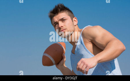 Muscular american football player ready to throw ball in hand. Outdoors shot Stock Photo