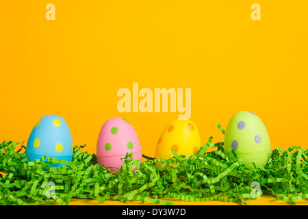 4 assorted colored Easter eggs on a yellow background Stock Photo