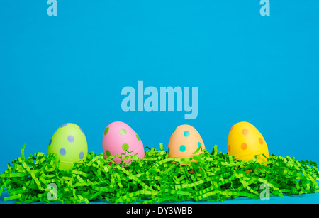 4 assorted colored Easter eggs on a sky blue background Stock Photo