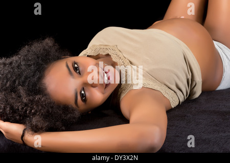Happy pregnant african woman lying on a black fur Stock Photo