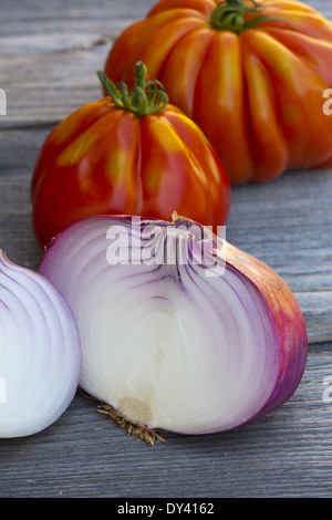 Coeur de Boeuf Tomatoes and large red Onions from Weekly Market in South France on a old wooden Table Stock Photo