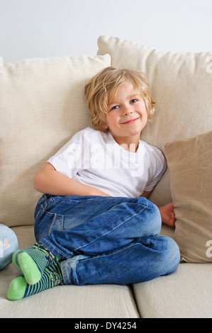 Young boy sitting on sofa looking at camera Stock Photo