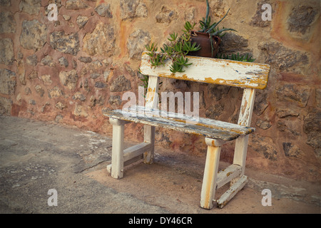 Empty Rustic wooden outdoor cottage bench painted white against wall Stock Photo