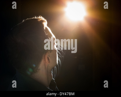 Young man starring at the bright light in the dark Stock Photo
