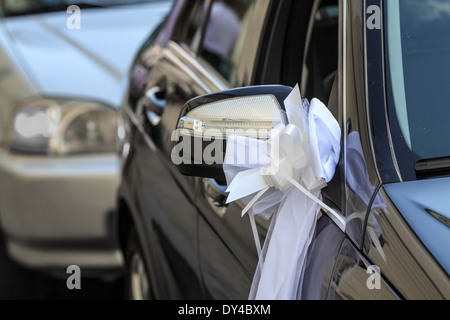 A traditional wedding car decorated with ribbons and flowers waits