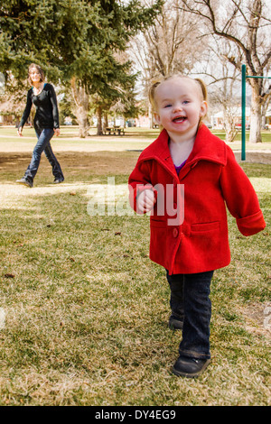 Beautiful young mother playing with adorable, cute 16 month baby girl on park playground Stock Photo
