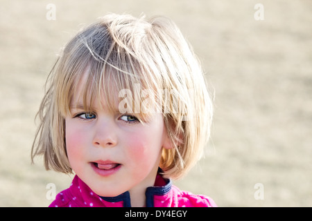 Little girl with wary look and tongue sticking out Stock Photo