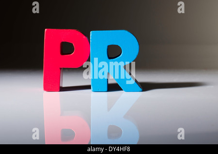Multicolored text PR made of wood. White background Stock Photo
