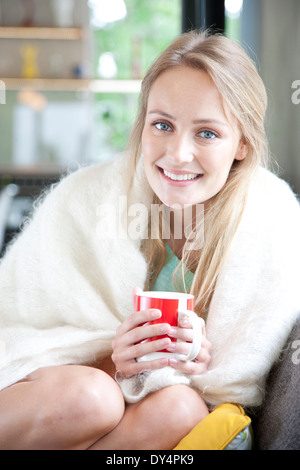 Young Woman Curled up on Sofa Holding Mug