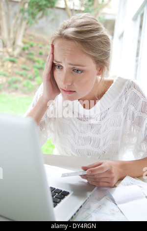 Upset Woman Holding Credit Card Looking at Laptop Screen