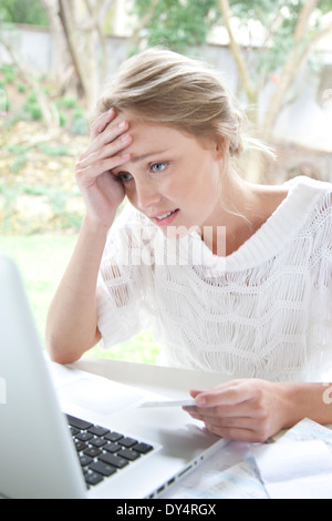 Upset Woman Holding Credit Card Looking at Laptop Screen