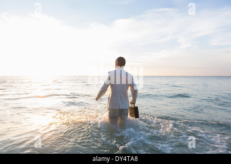 Businessperson standing in sea, rear view