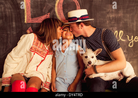 Father and mother kissing daughter on cheek Stock Photo