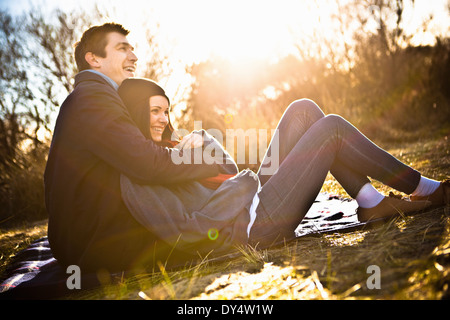 Couple sitting on picnic blanket hugging Stock Photo