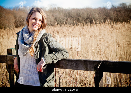 Portrait of young woman leaning against fence Stock Photo