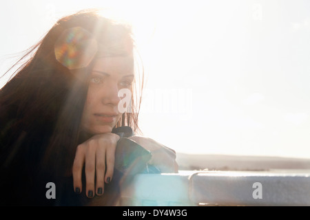 Close up of young woman leaning against fence Stock Photo