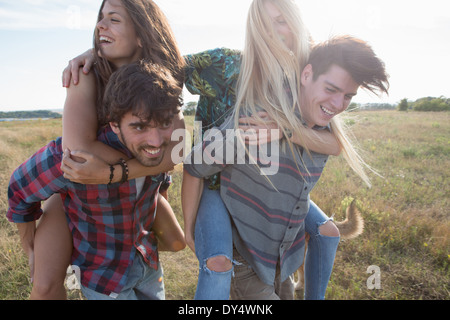 Young men giving women piggy backs Stock Photo