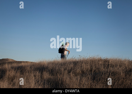 Distant view of mature man hiking in hills and long grass Distant view of mature man hiking in hills and long grass
