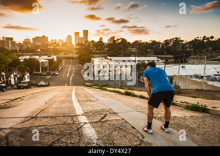 Young male runner taking a break at the top of a steep city hill Stock Photo