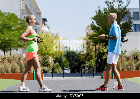 Young woman and trainer using exercise ropes in park Stock Photo