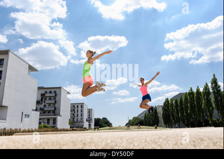 Two young women doing jump exercises Stock Photo