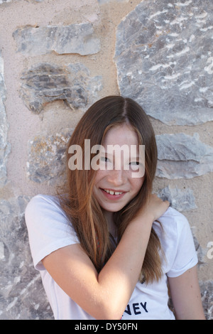 Portrait of shy smiling girl leaning against wall Stock Photo
