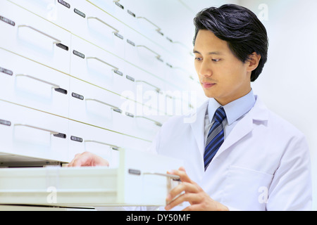 Male pharmacist searching for medications in pharmacy Stock Photo