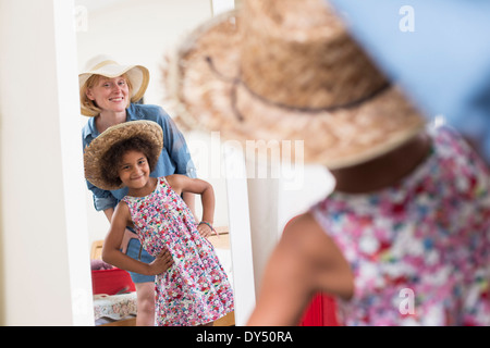 Mother and daughter looking in mirror wearing sunhats Stock Photo