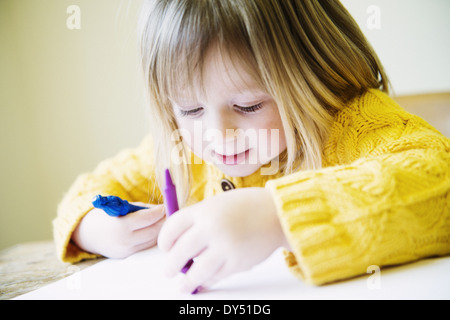 Young girl at kitchen table coloring in with felt pens Stock Photo