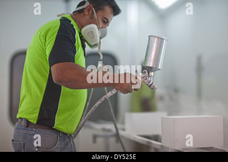 Man spraying wooden products in carpenters workshop Stock Photo